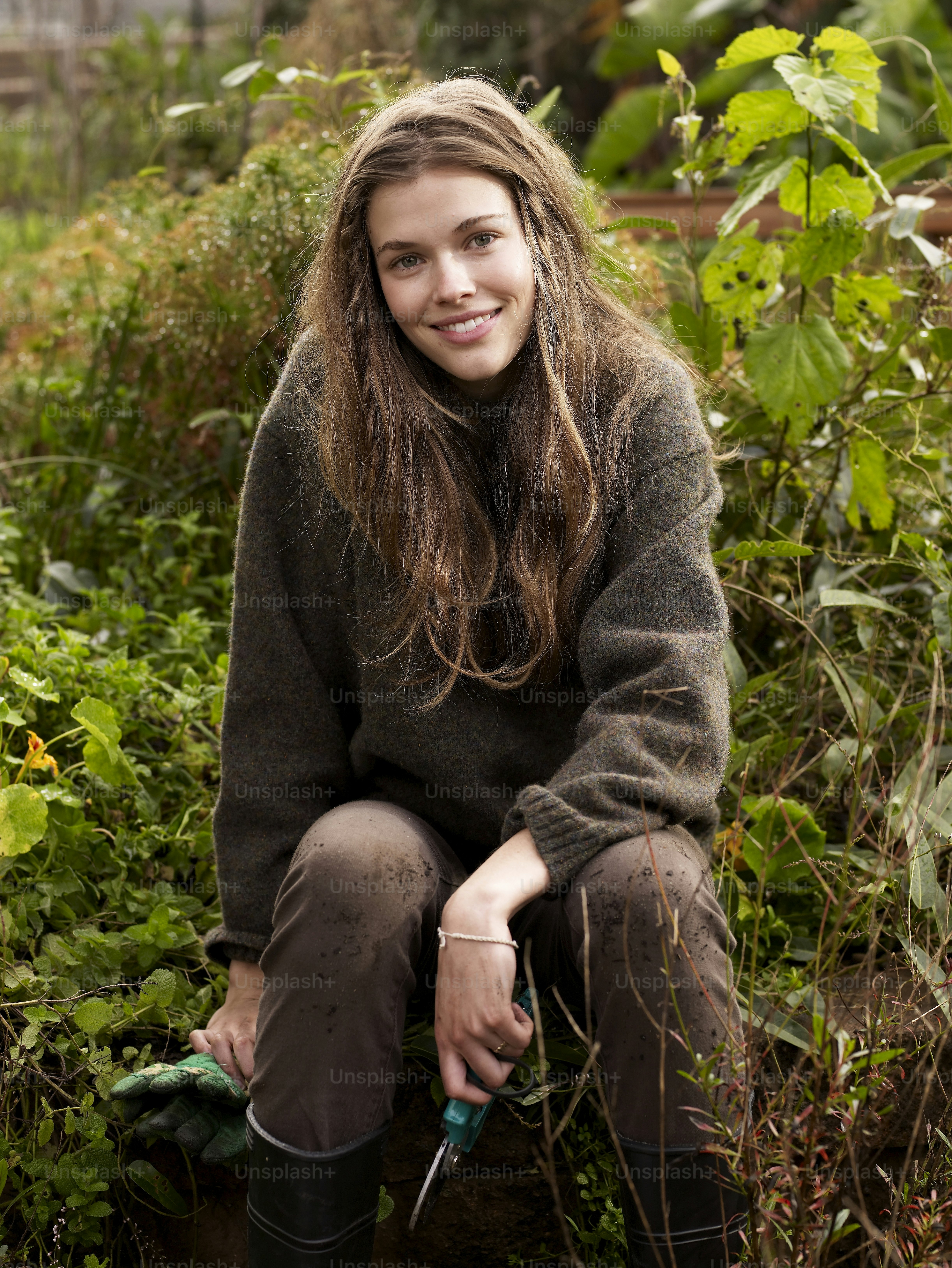 정원에 앉아 정원 가꾸기 도구를 들고 있는 여자