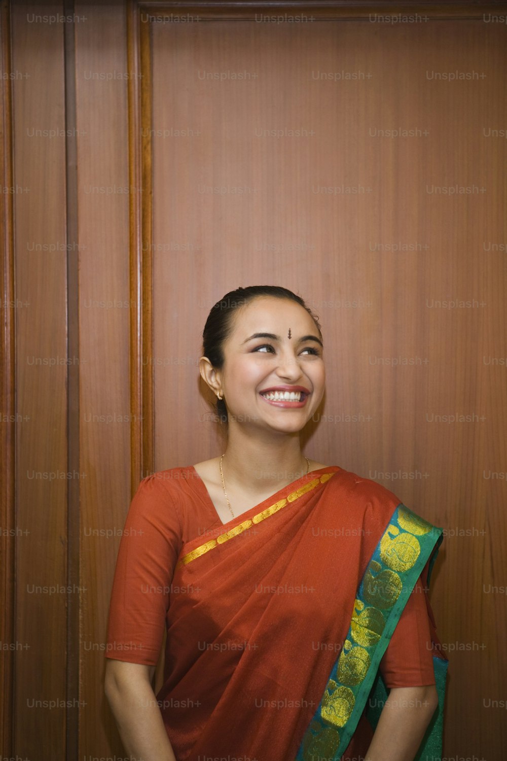 Una donna in un sari rosso sorride per la macchina fotografica