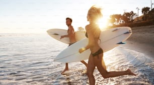 Dos surfistas corriendo hacia el mar con sus tablas de surf
