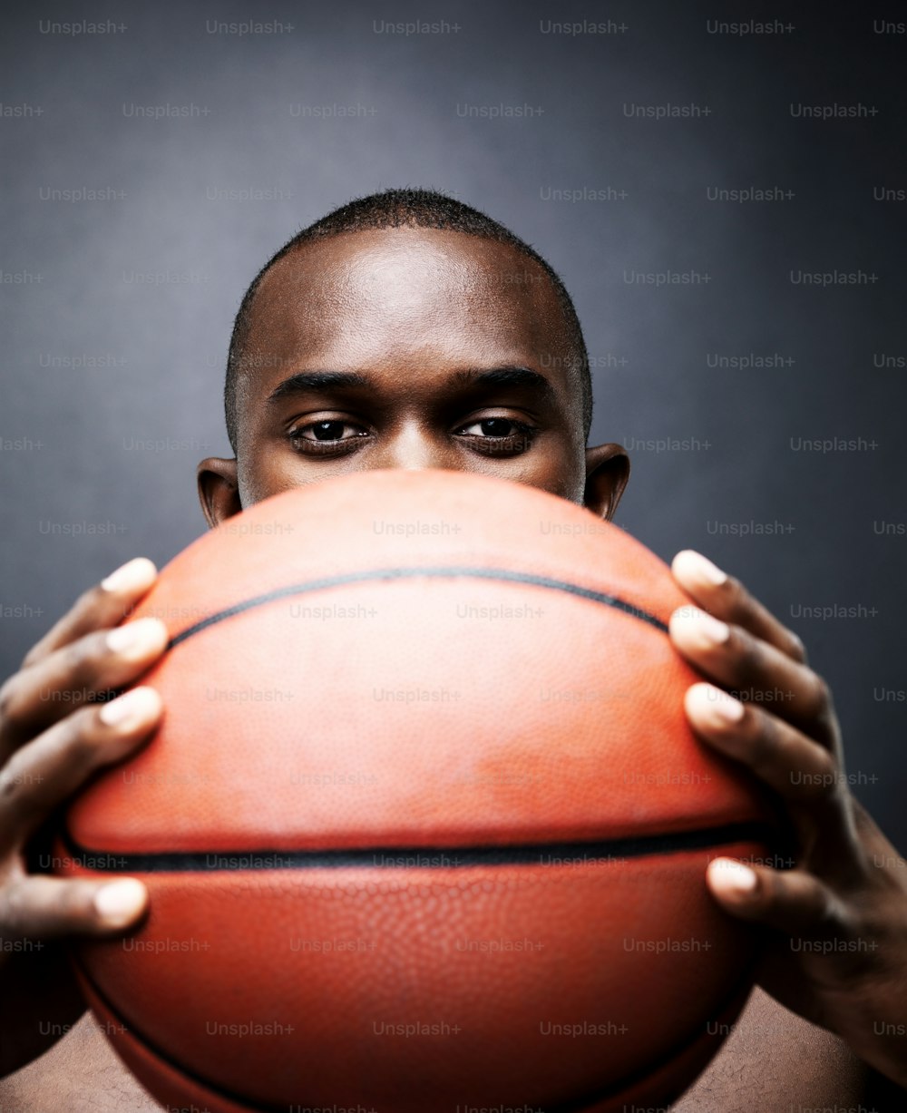 a man holding a basketball in front of his face