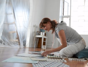 a woman sitting on the floor painting a picture