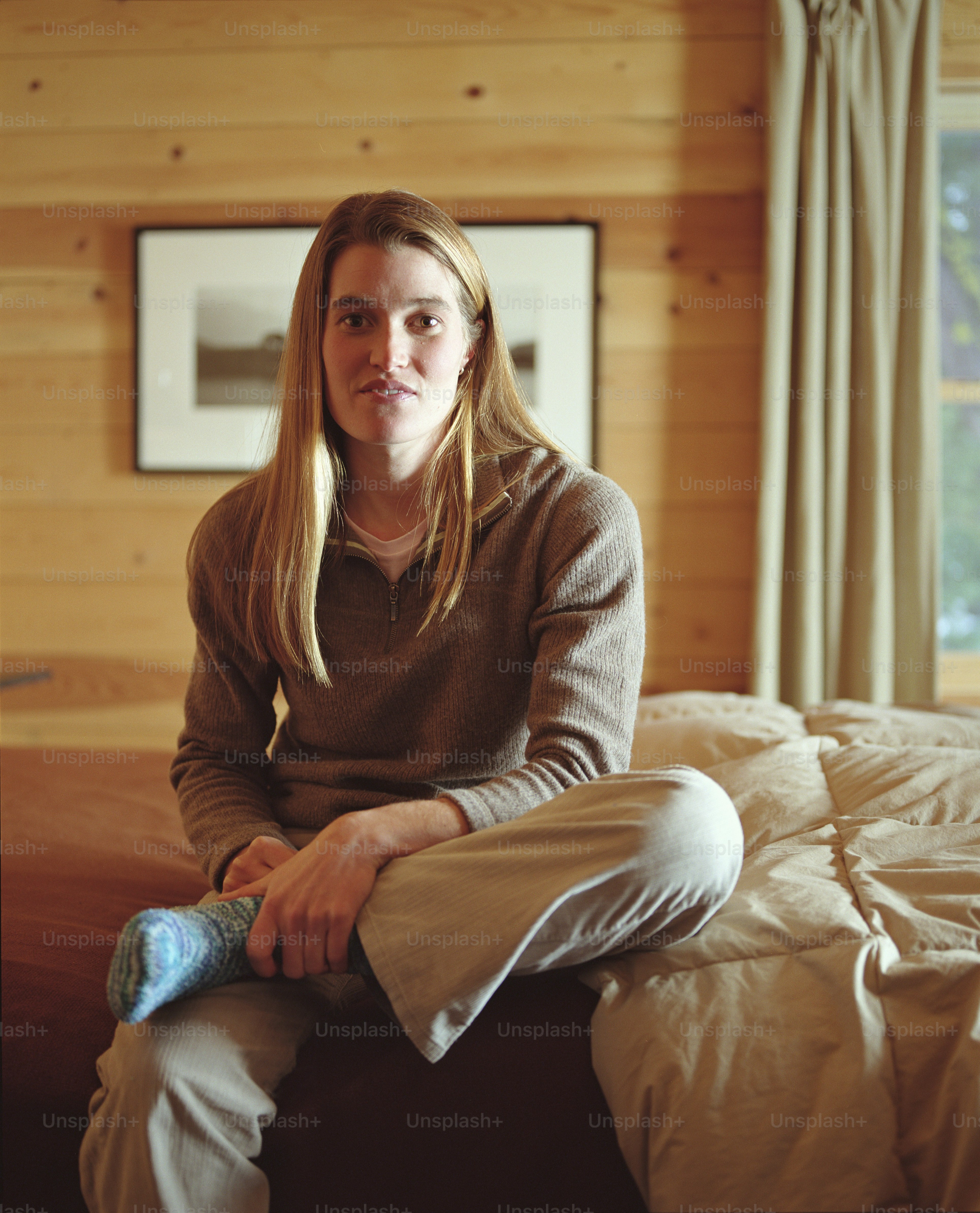 Young woman sitting on bed, legs crossed at knee, portrait