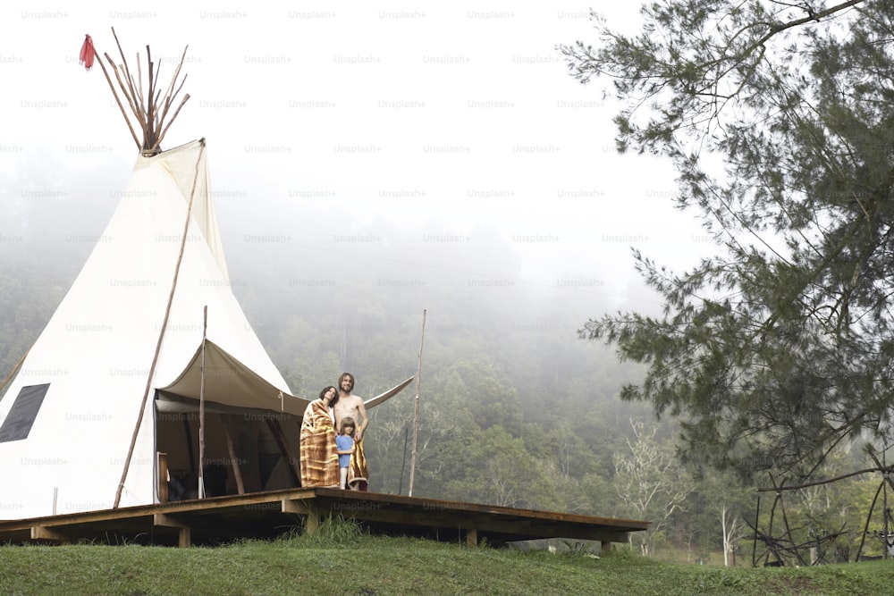 a couple of people standing in front of a teepee