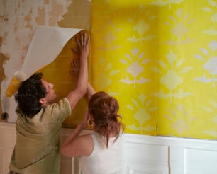 a man and a woman are painting a wall