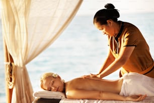 a woman getting a back massage at the beach