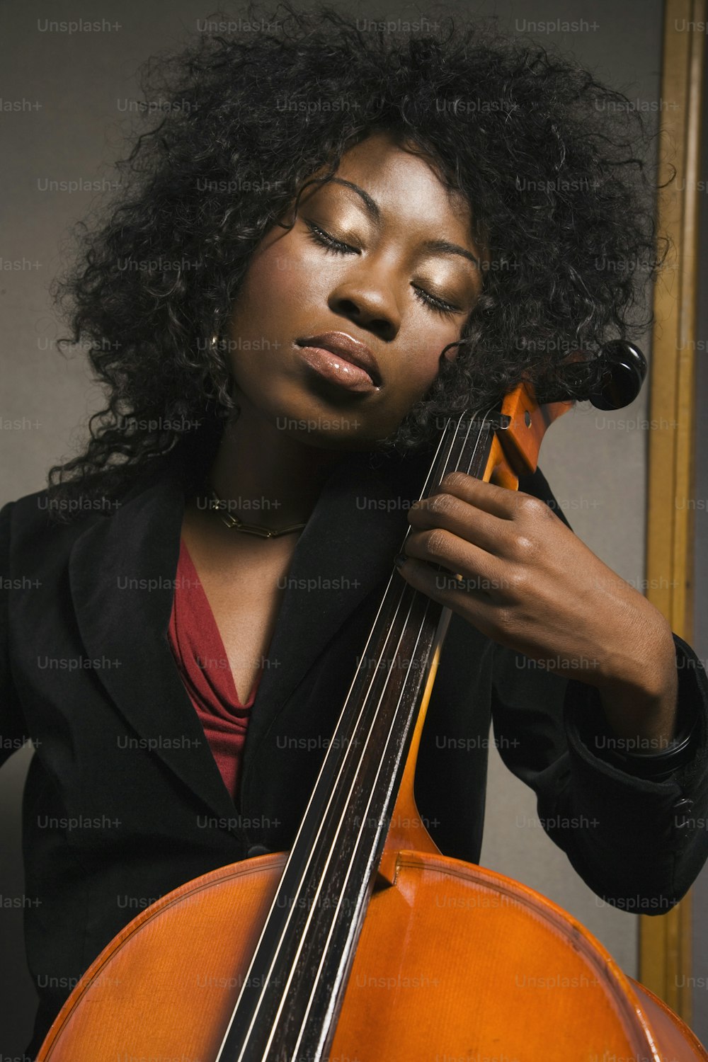 uma mulher segurando um violoncelo na mão direita