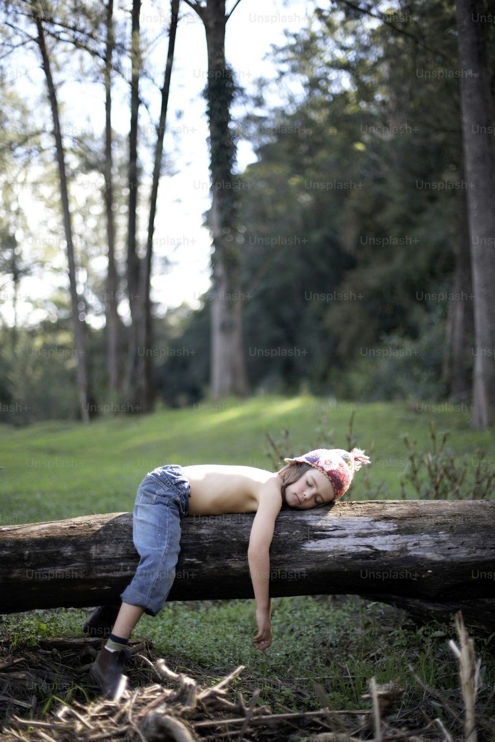 a young boy laying on a log in the woods