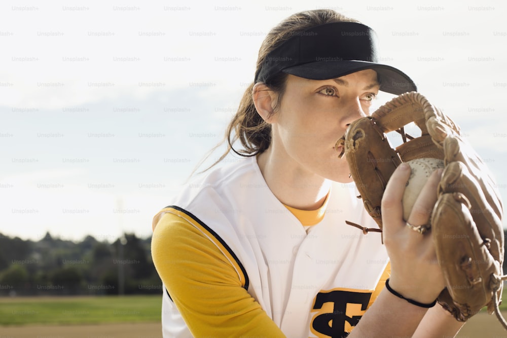a woman in a baseball uniform holding a catchers mitt