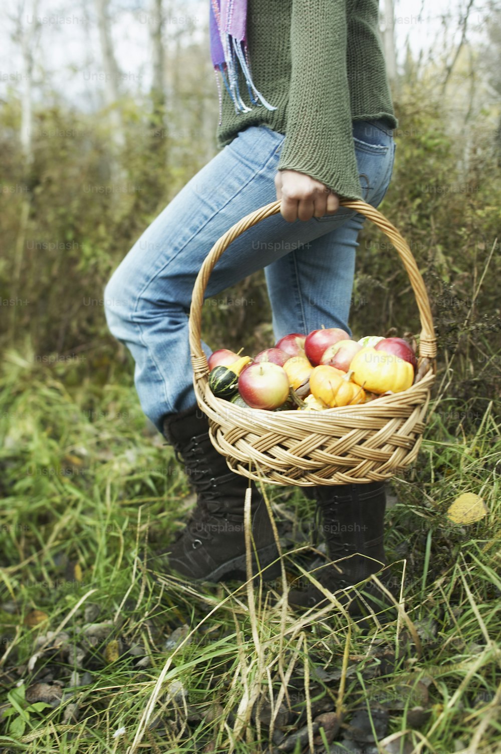 Una persona sosteniendo una canasta llena de manzanas