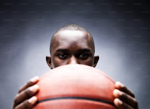 a man holding a basketball in front of his face