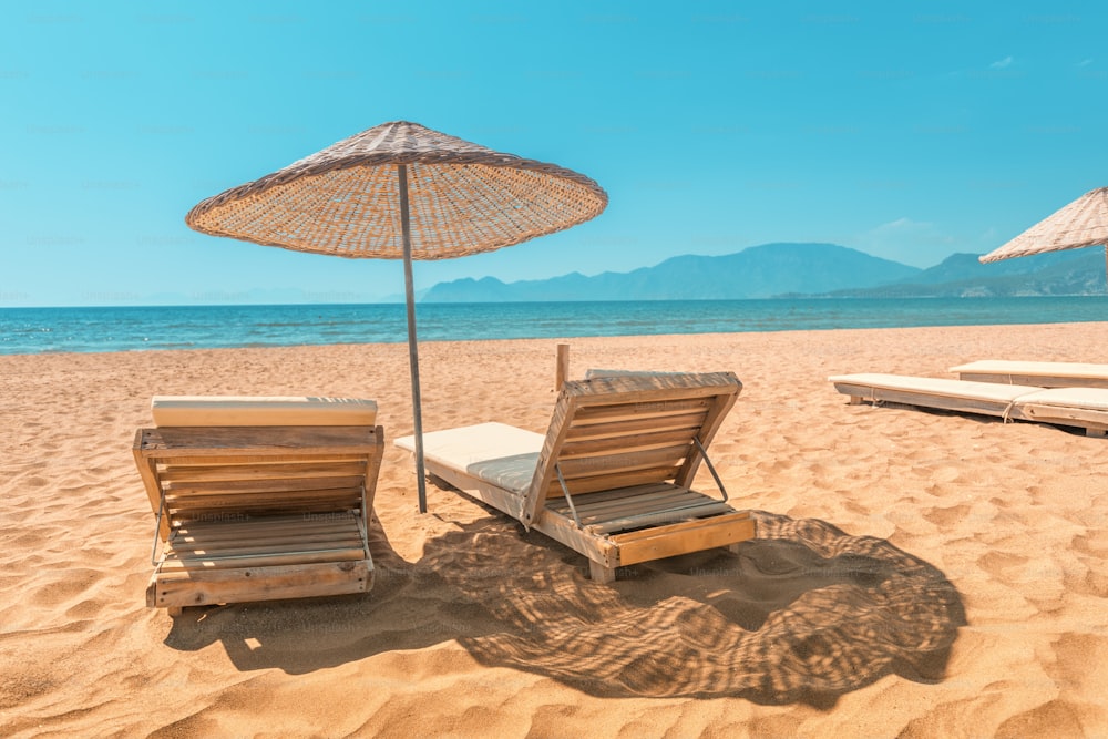 Espreguiçadeira e guarda-sol na praia de areia vazia durante a baixa temporada, ou no início da manhã. Paraíso marítimo e oceânico e conceito de férias