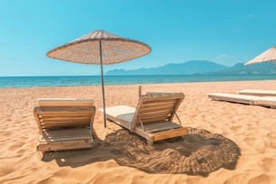 Sunbed and parasol on empty sandy beach during low season, or early in the morning. Sea and ocean paradise and vacation concept
