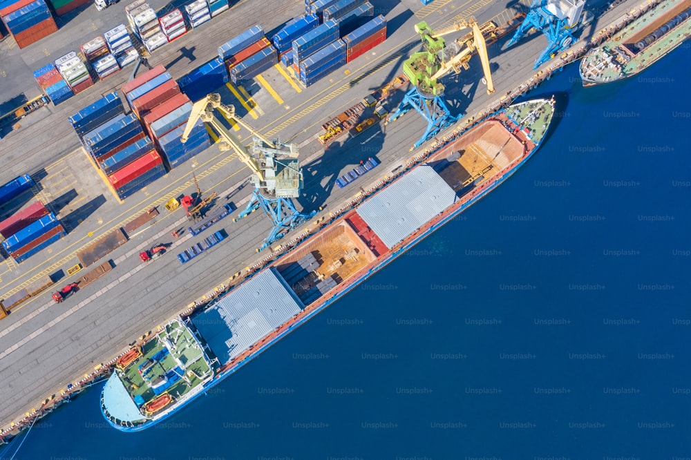 Luftbild Draufsicht riesiges Frachtschiff, das am Pier am Hafen vor Anker liegt und Waren, Metall, Beton und andere feste Rohstoffe lädt