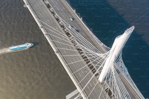 Schrägseilbrücke über die Flussmündung, Luftaufnahme von der Spitze der Brückenstütze. Boot schwimmt auf dem Wasser