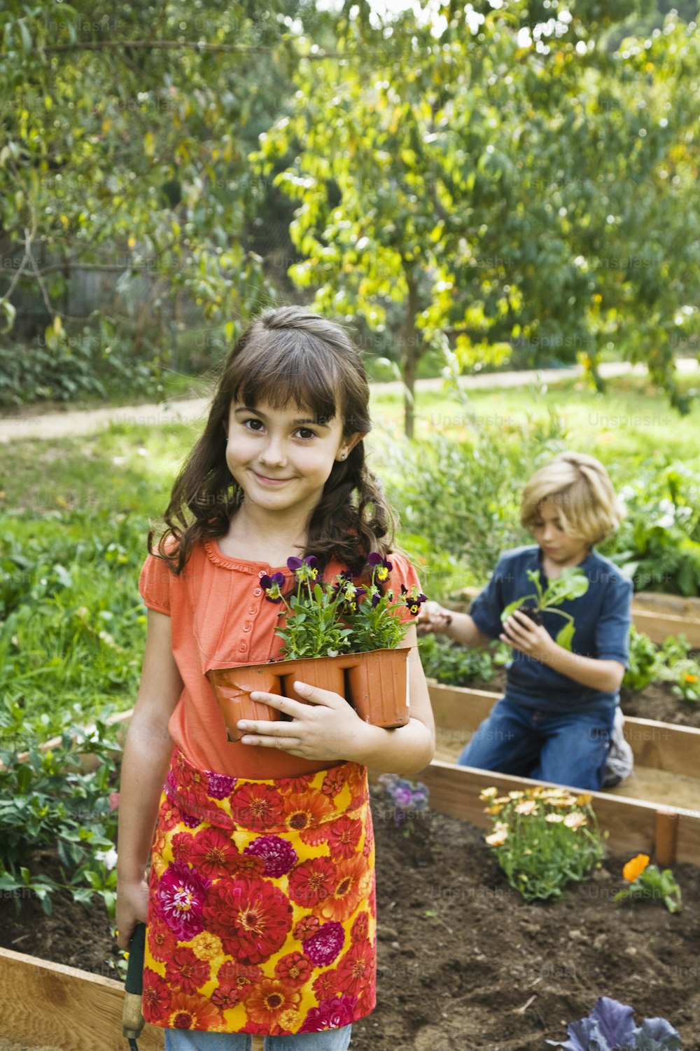 a young girl holding a potted plant in a garden