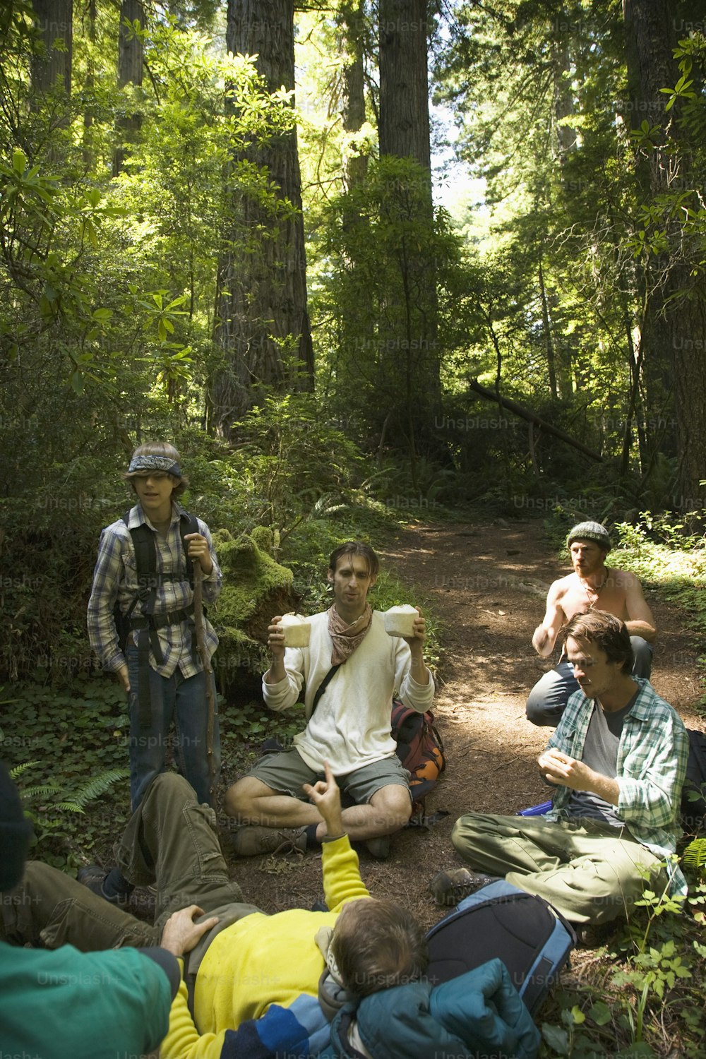 a group of people sitting on the ground in the woods