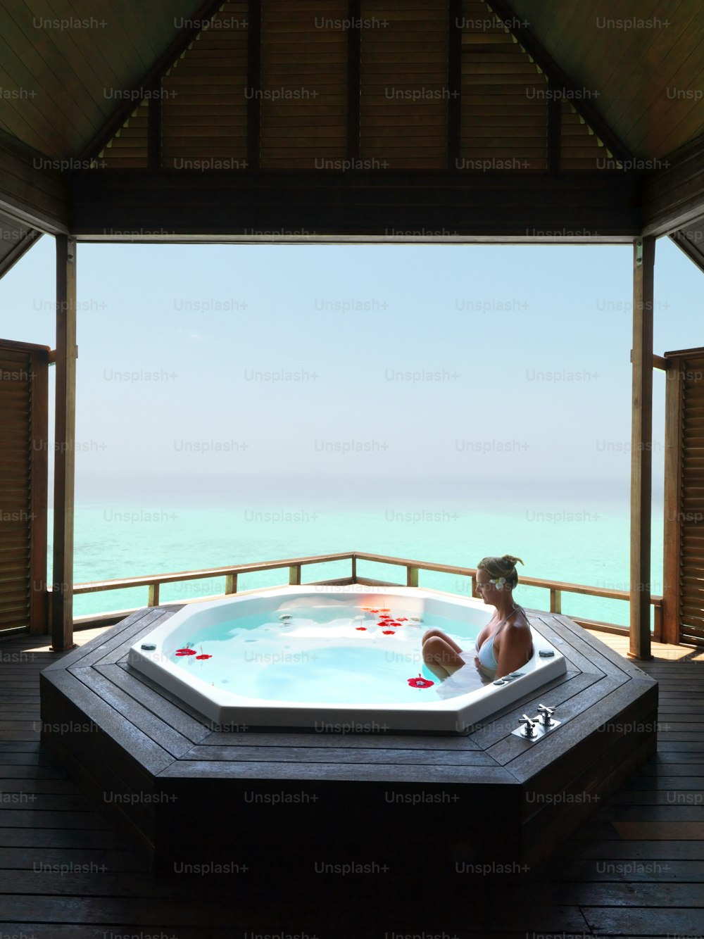 Mature woman relaxes in a hot tub with a pristine, blue ocean in the background