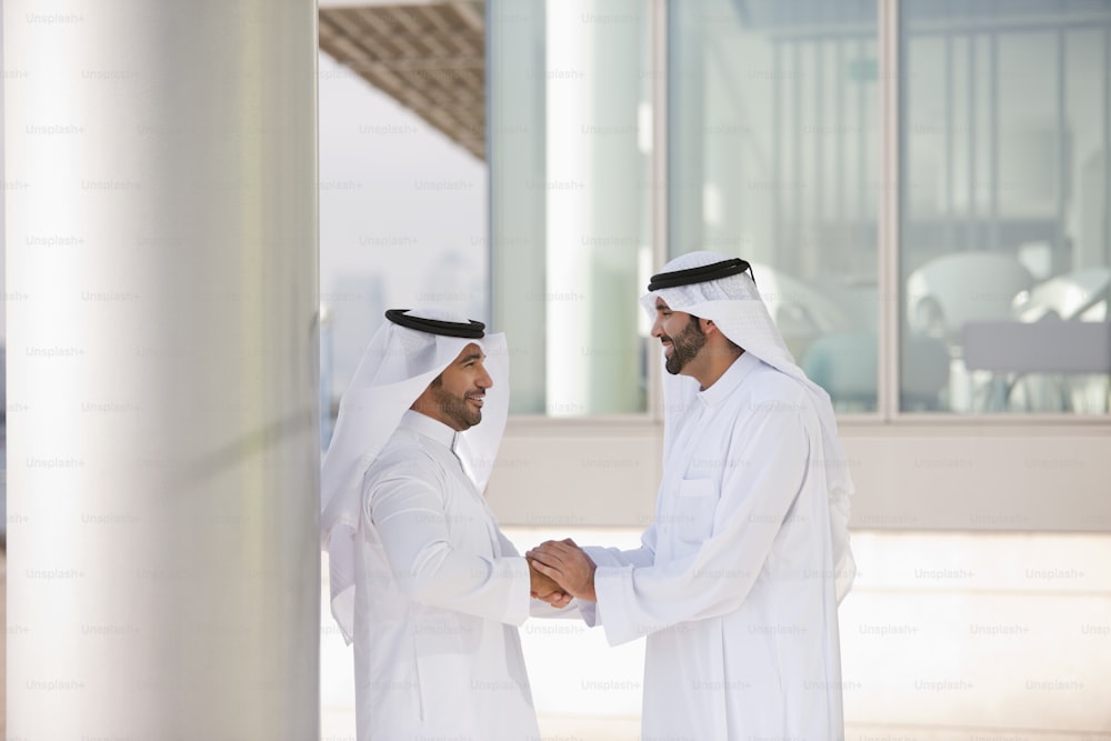 two men shaking hands in front of a building