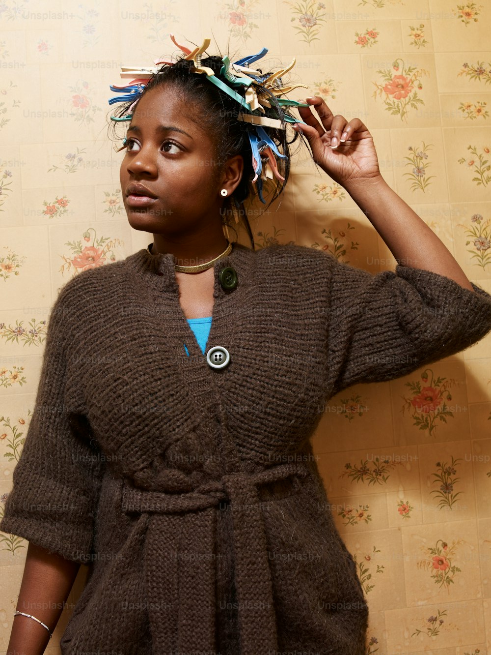 a woman wearing a brown sweater and a blue necklace