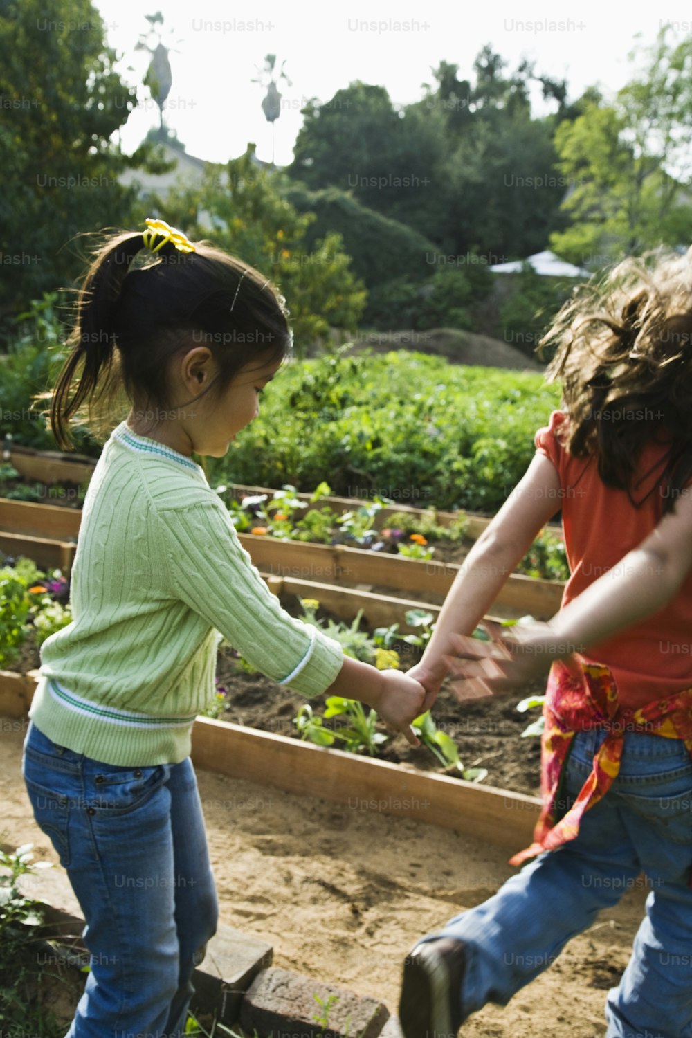 two young girls holding hands in a garden