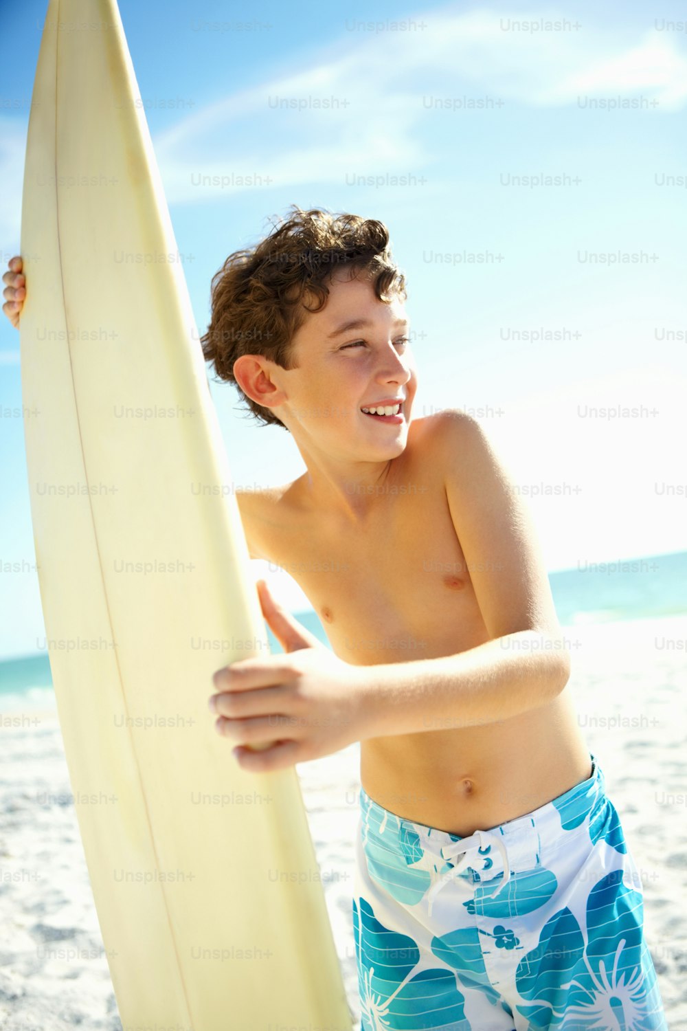 a young man holding a surfboard on a beach