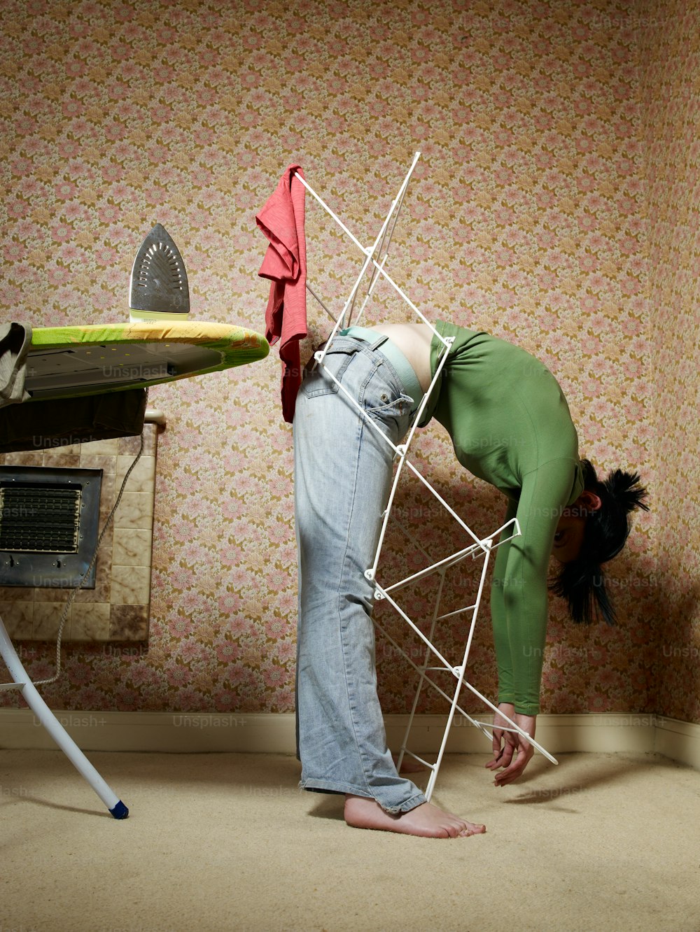 Una mujer inclinada con una tabla de planchar en la espalda