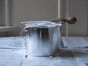a metal bucket with a wooden handle on top of a table