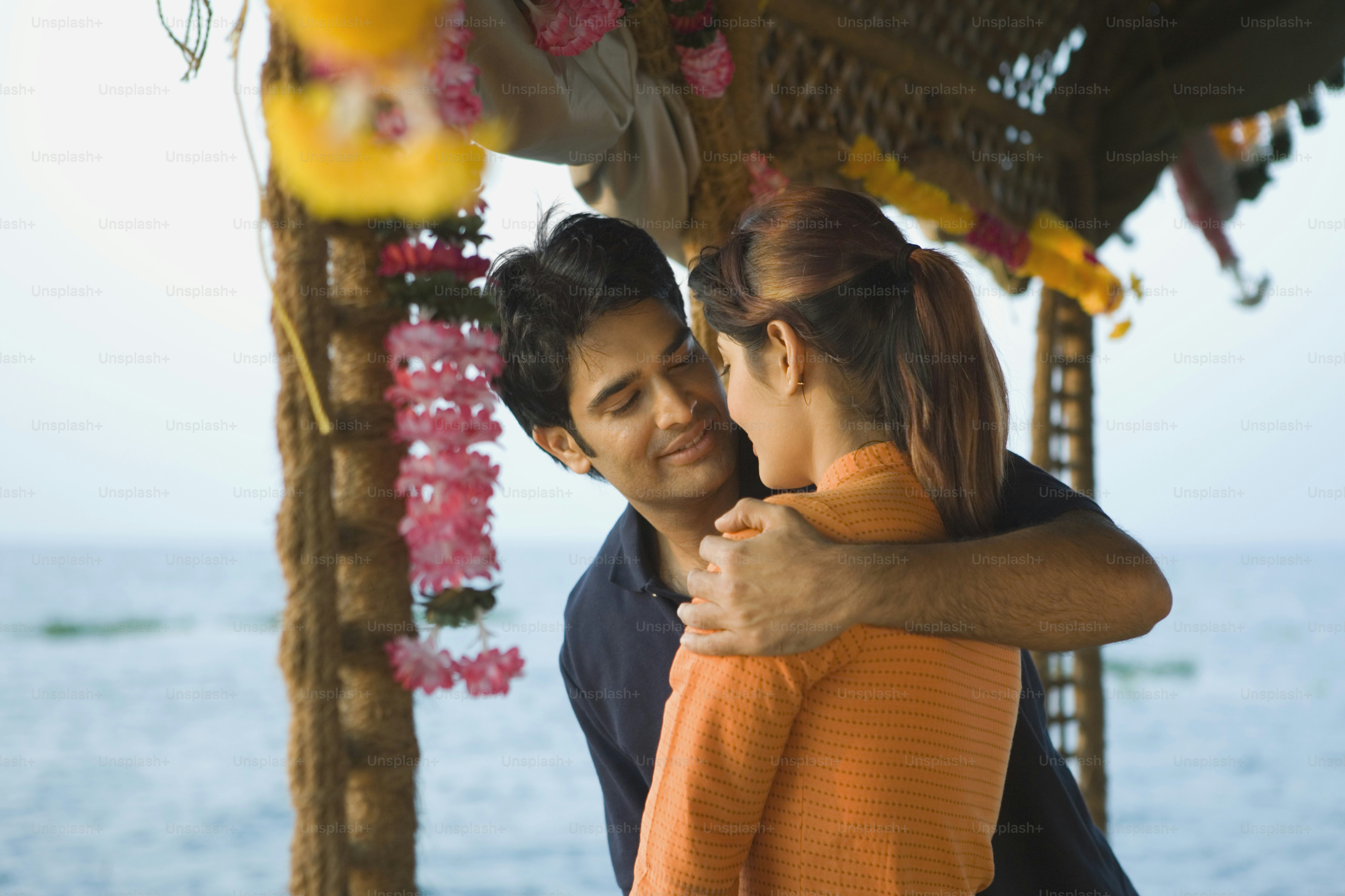 A man and woman embracing each other in front of a body of water photo ...
