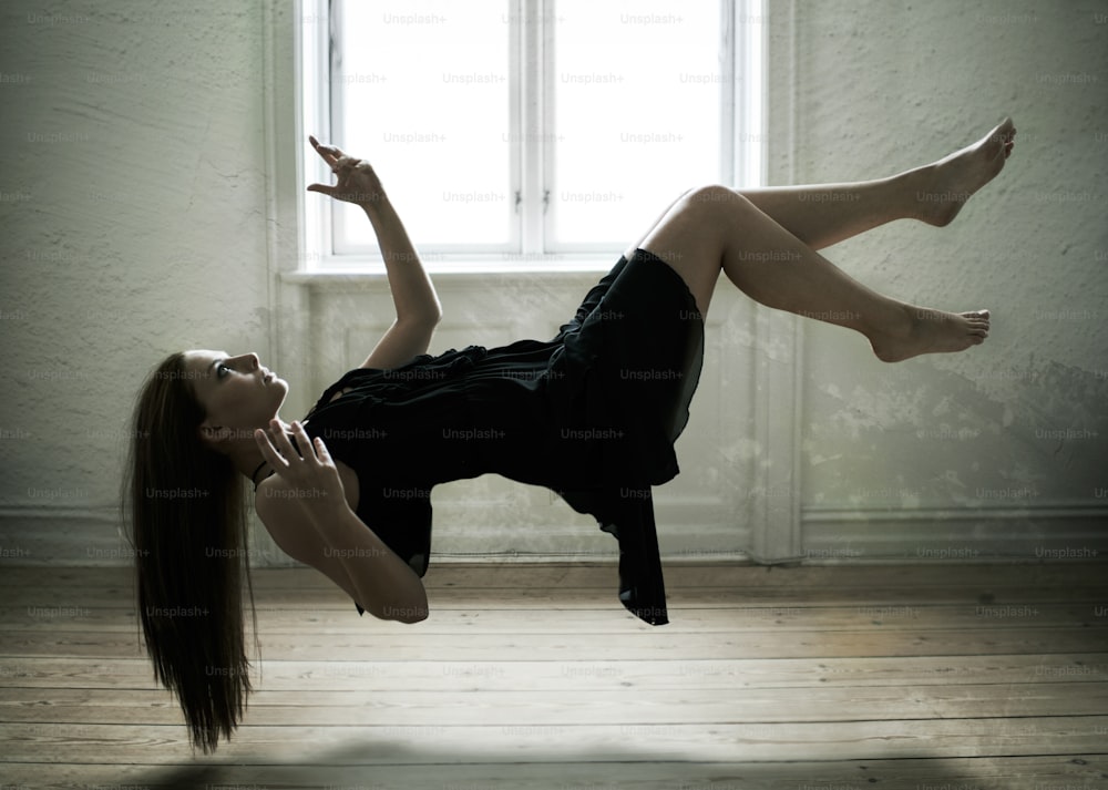 a woman in a black dress laying on the floor