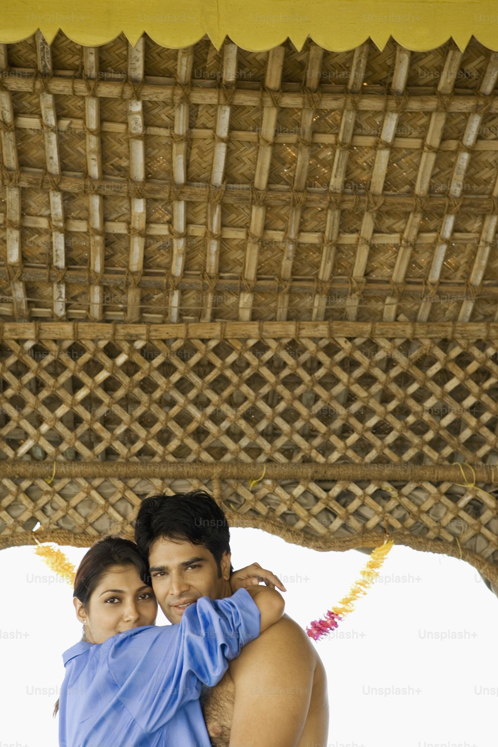 a man and a woman standing under a thatched roof