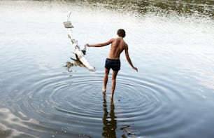 um homem parado em um corpo de água ao lado de um barco
