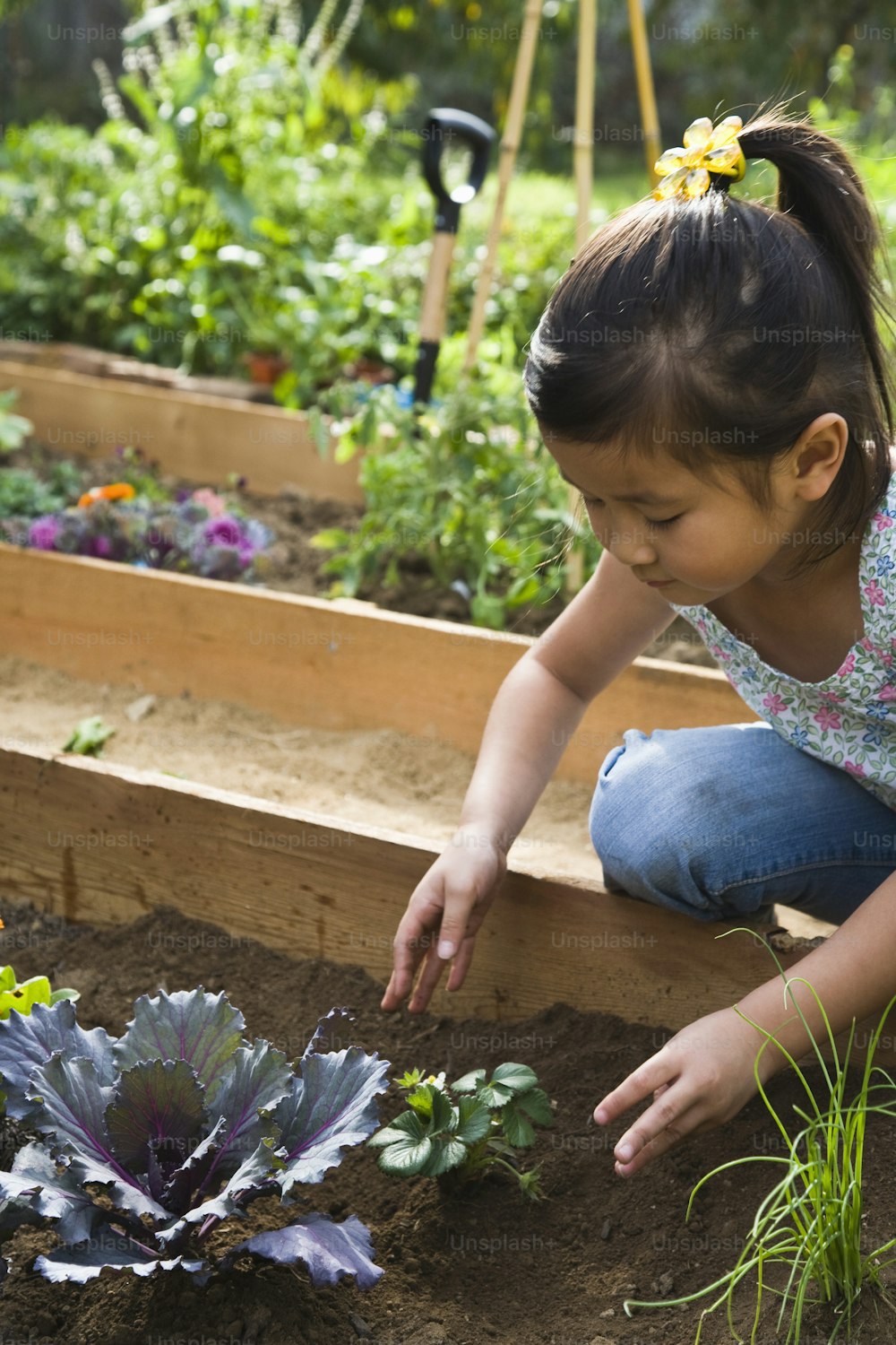 a little girl kneeling down in a garden