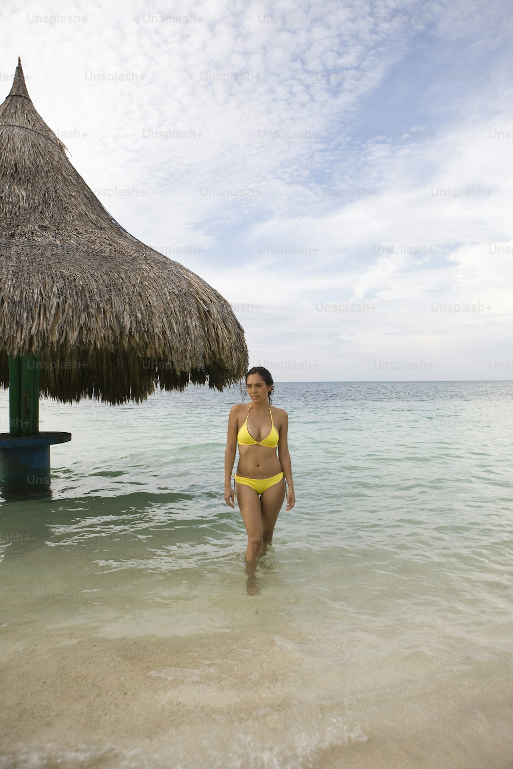 Una mujer en bikini amarillo caminando hacia el océano