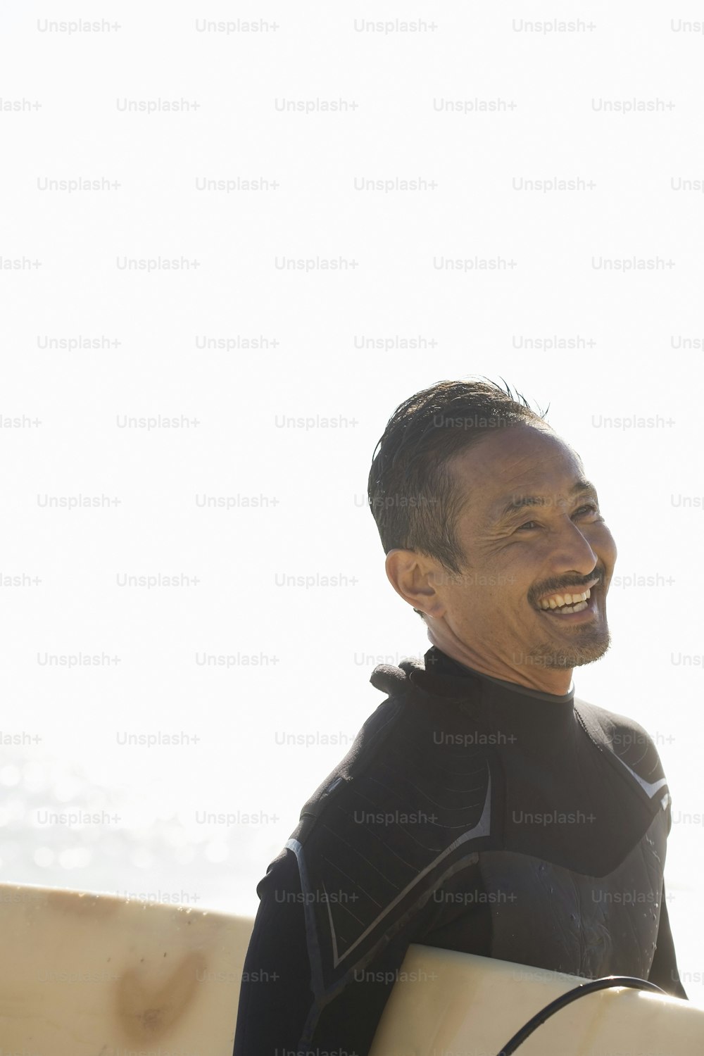 a man in a wet suit holding a surfboard