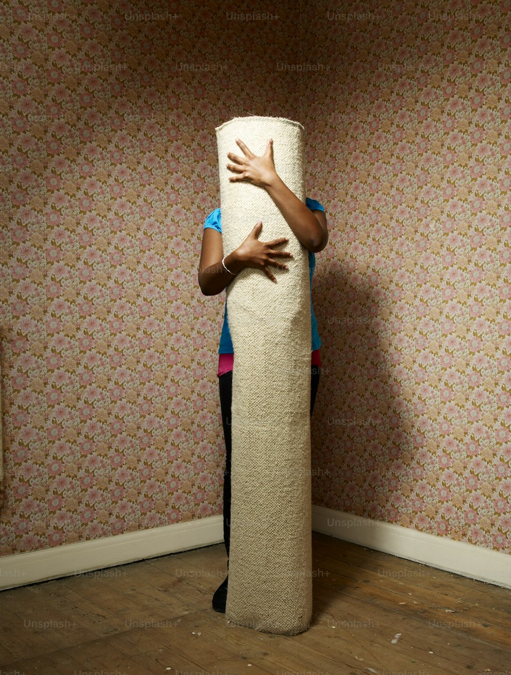 Eine Frau versteckt sich hinter einer großen Rolle Toilettenpapier