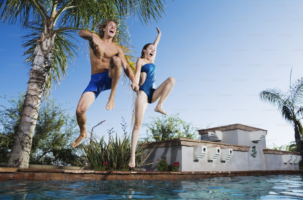 um casal de pessoas pulando em uma piscina