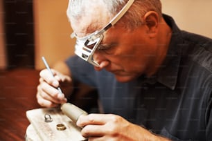 Un hombre con gafas trabajando en un trozo de madera