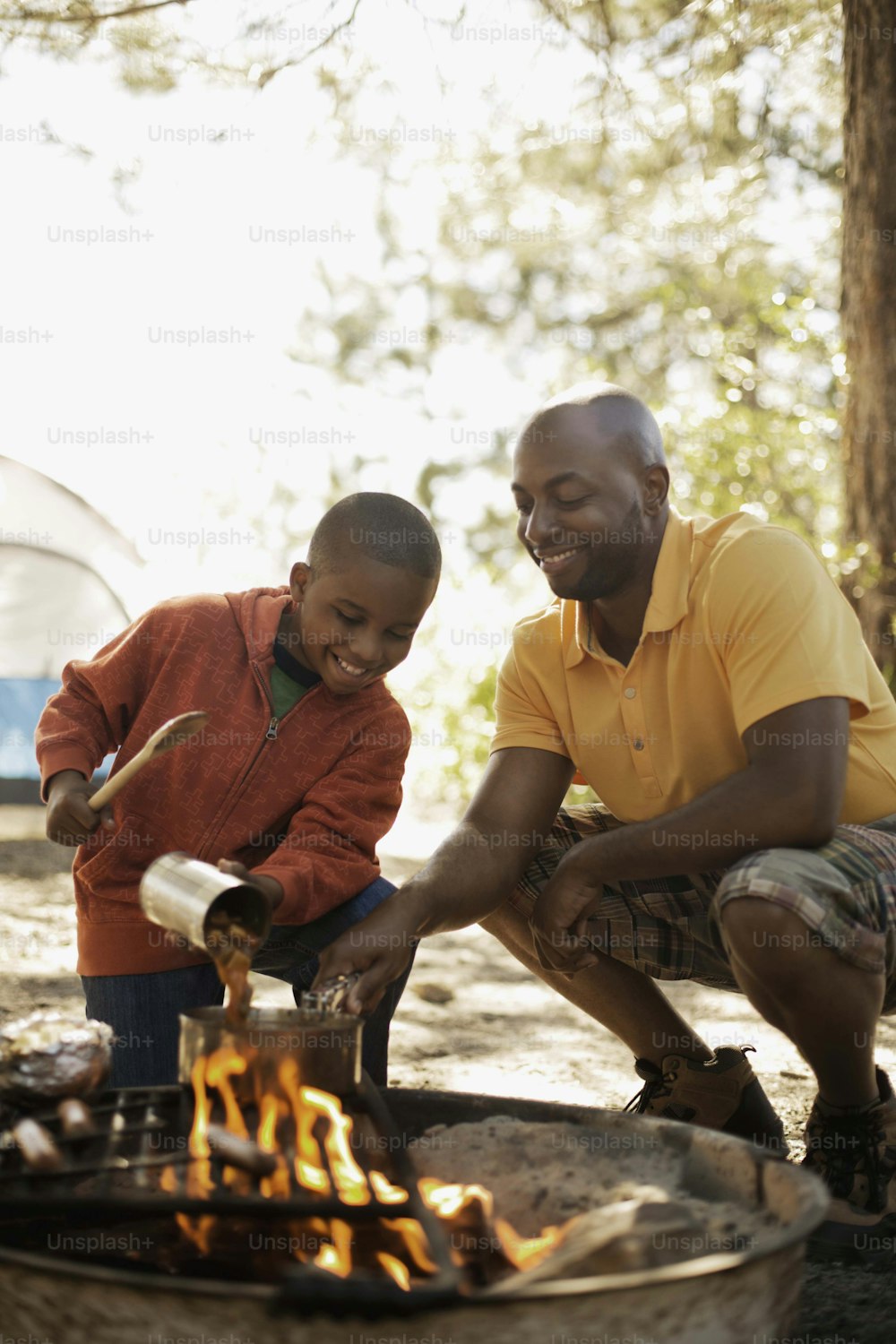 a man and a boy are cooking over a campfire