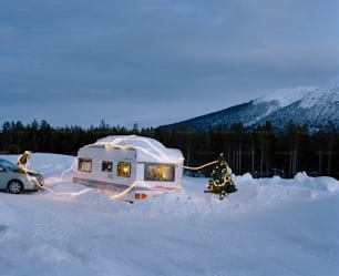 Un camping-car garé dans la neige avec un sapin de Noël devant lui