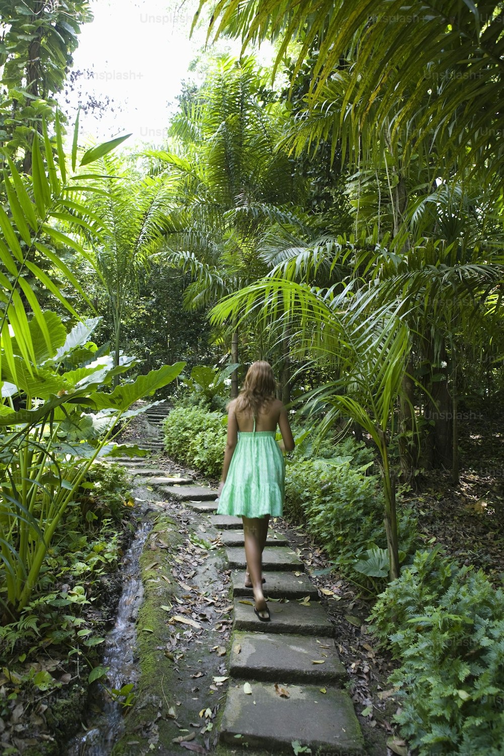 a woman in a green dress walking down a path