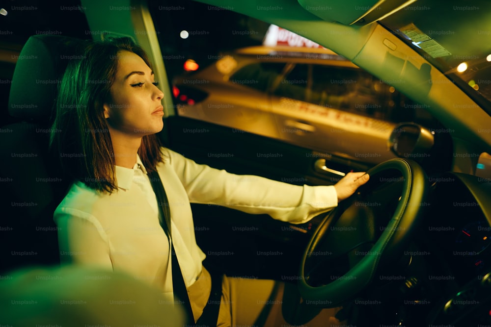 Mujer cansada que se siente somnolienta mientras conduce un automóvil por la noche.