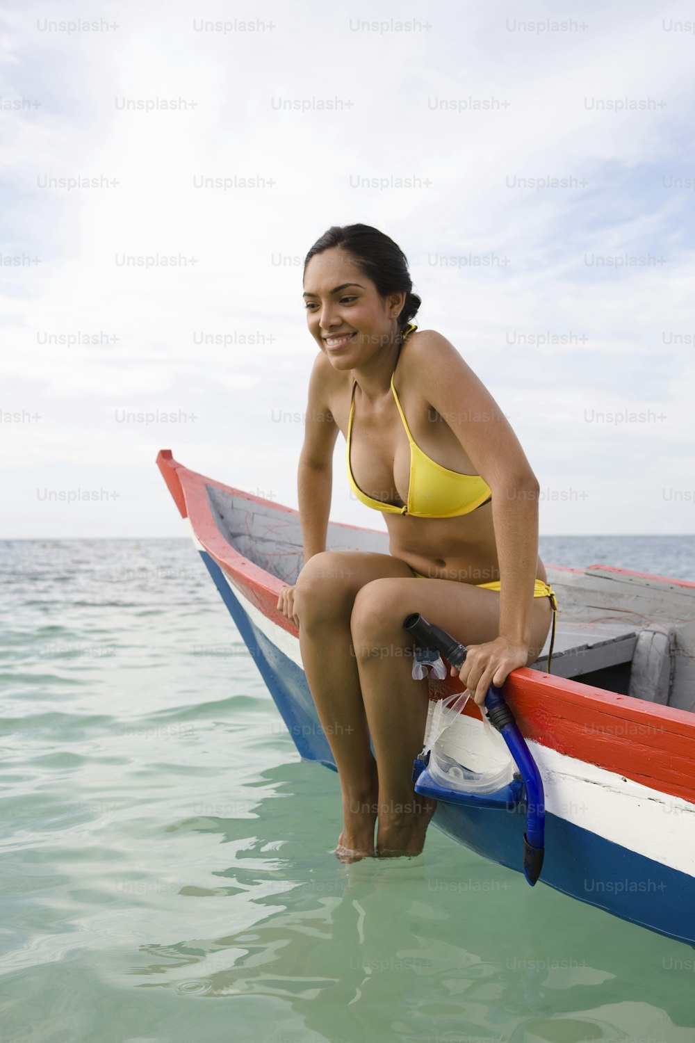 ボートに座っている黄色いビキニの女性