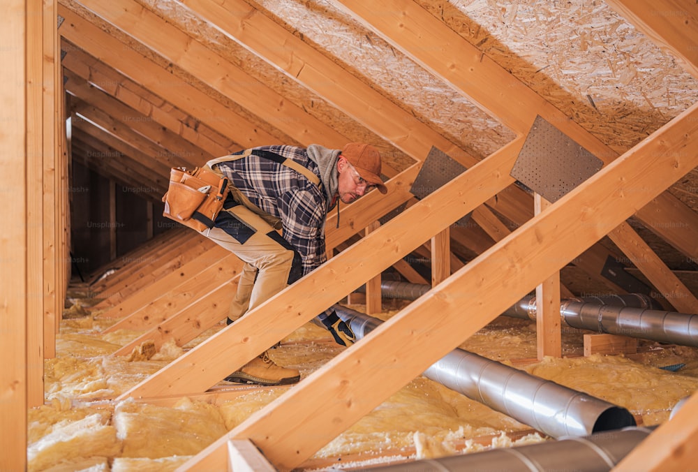 Caucasian Home Constractor Assembles HVAC Pipe System In Attic.