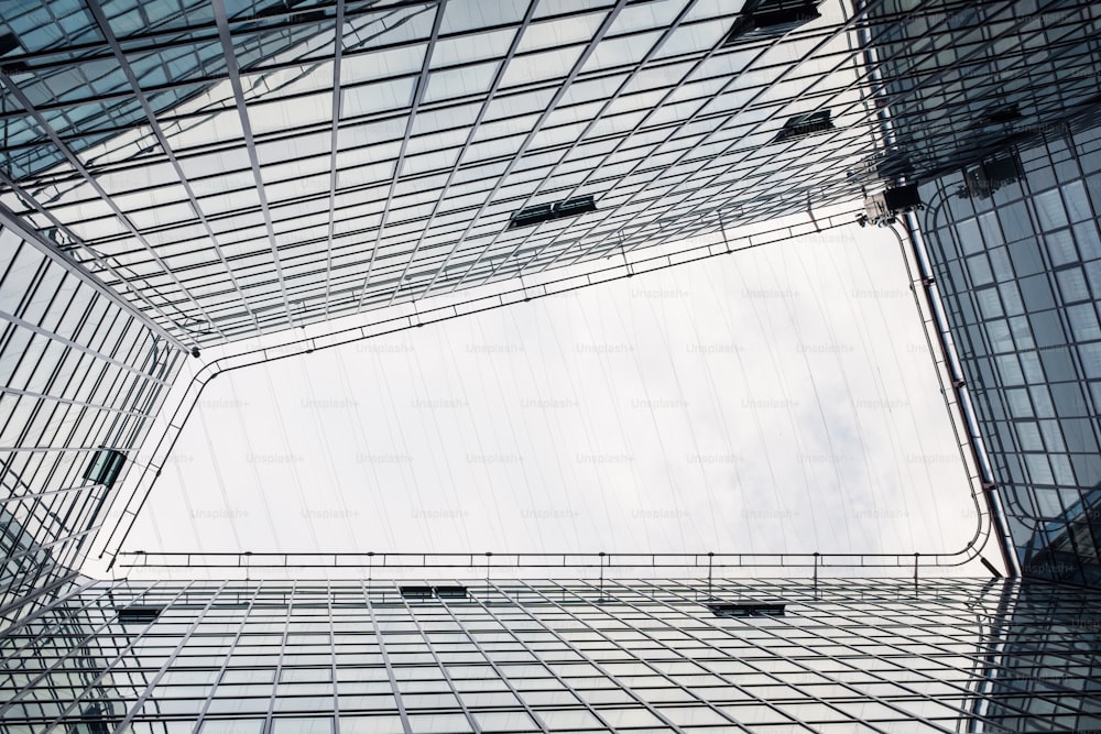 Low-angle view of a modern glass office building against a cloudy sky in Madrid, Spain.e