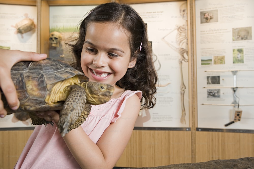 Una niña pequeña sosteniendo una tortuga en sus manos