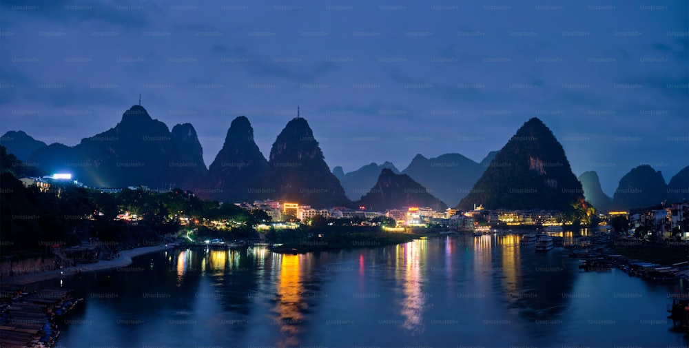 Panorama de la ciudad de Yangshuo iluminado por la noche con un espectacular paisaje montañoso kárstico de fondo sobre el río Li. Yangshuo, China