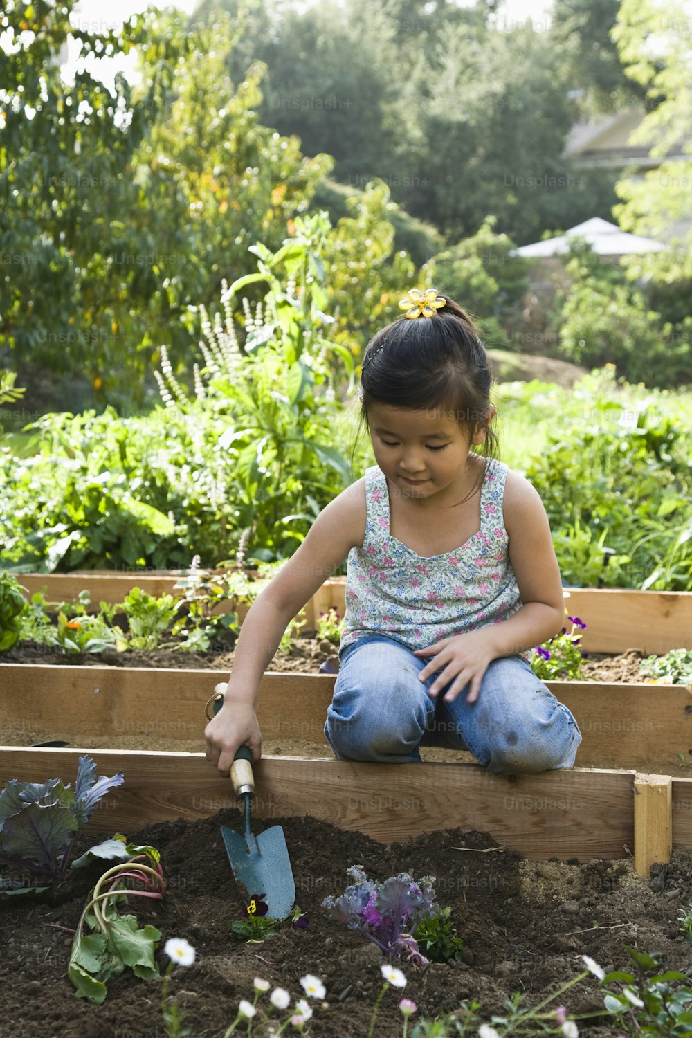 a little girl kneeling down in a garden