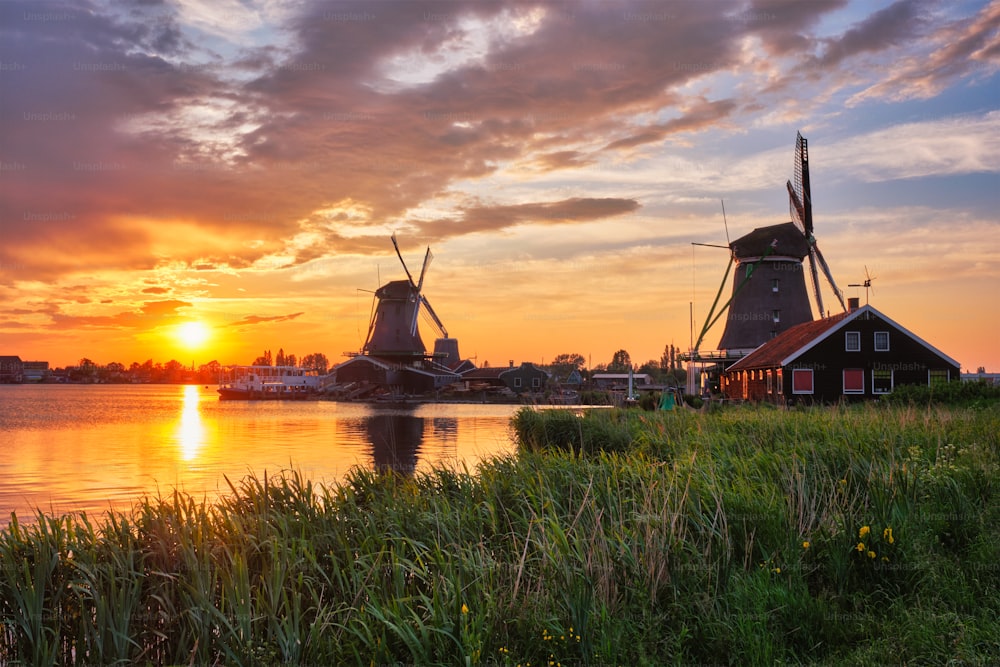 Escena rural de los Países Bajos - - molinos de viento en el famoso sitio tur�ístico Zaanse Schans en Holanda en la puesta del sol con el cielo dramático. Zaandam, Países Bajos