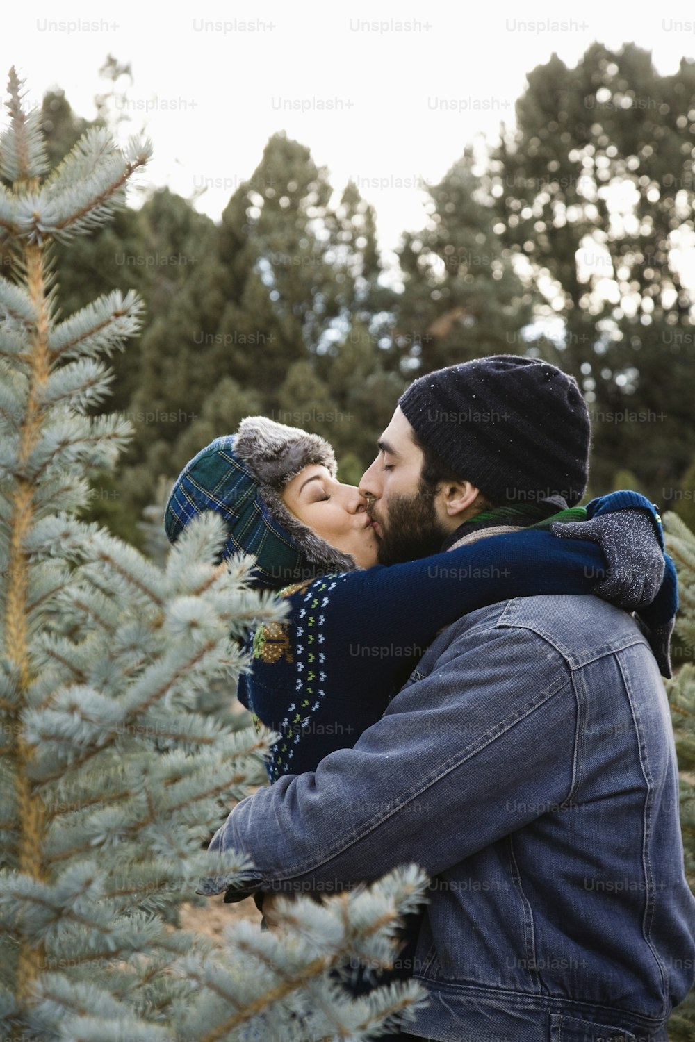 a man and woman kissing in front of a christmas tree