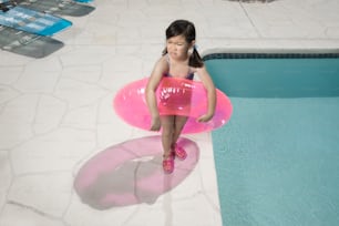 Ein kleines Mädchen, das auf einem aufblasbaren Poolschwimmer sitzt